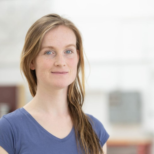 Junge Frau in blauem T-shirt vor hellem Hintergrund.